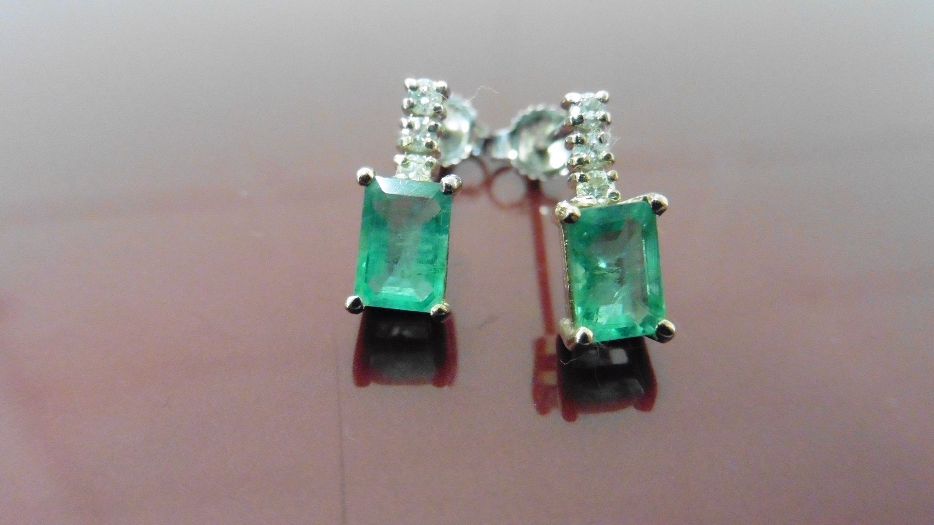 Emerald and diamond drop style earrings each set with an rectangular cut emerald, 6x4mm, weighing