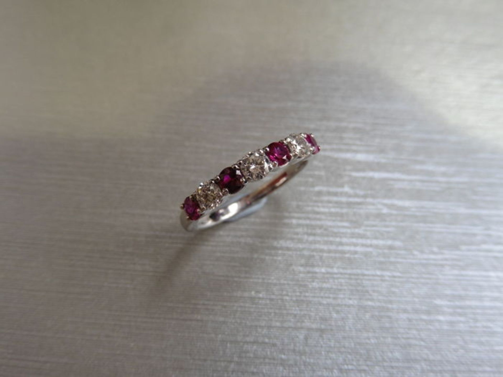 Ruby and diamond eternity style band ring with 4round cut rubies and 3 brilliant cut diamonds, 0.