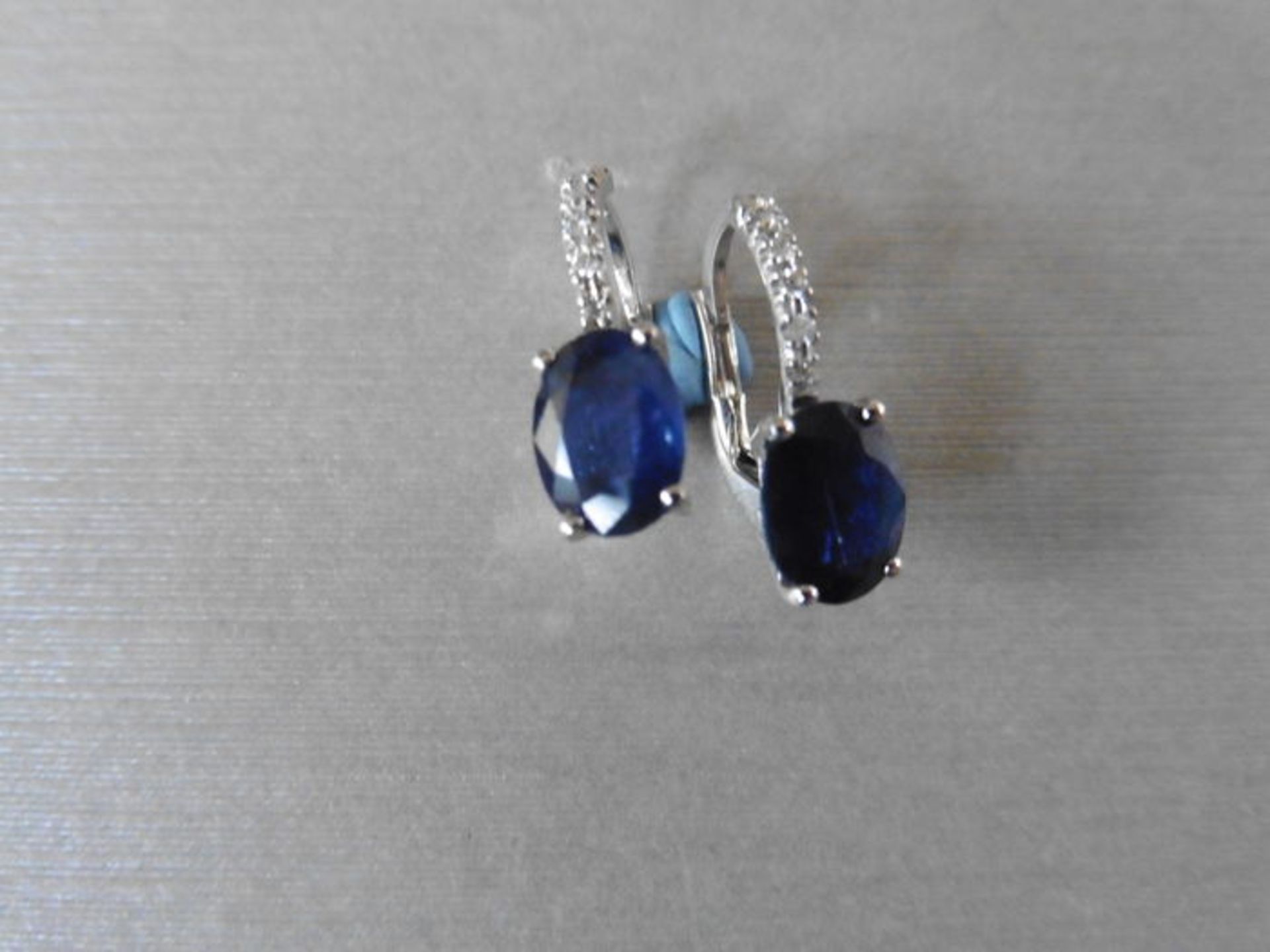 1.60ct sapphire and diamond hoop style earrings. Each is set with a 7x 5mm oval cut sapphire (