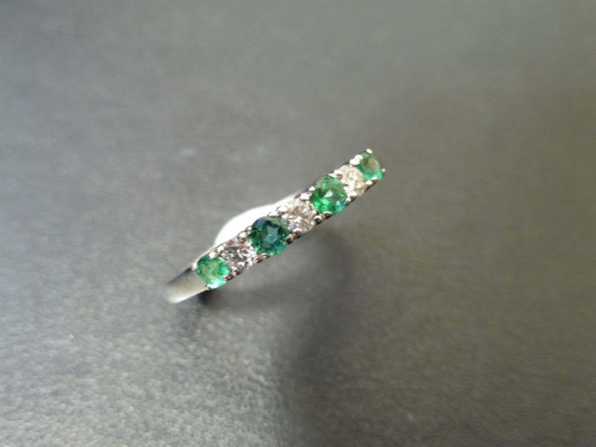 0.40ct emerald and diamond eternity style ring. Set with 4 round cut emeralds and 3 diamonds. Size