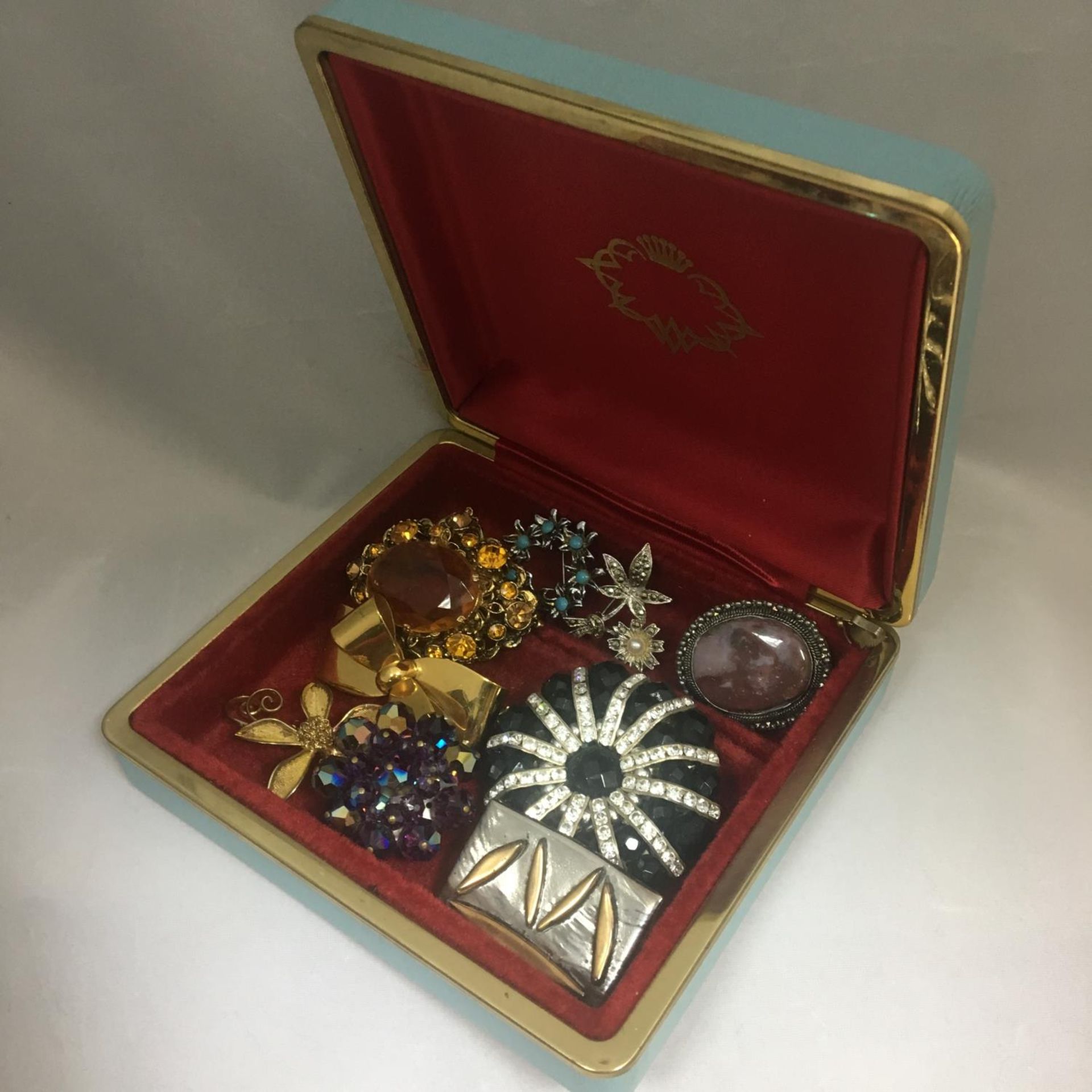 A box containing various vintage brooches