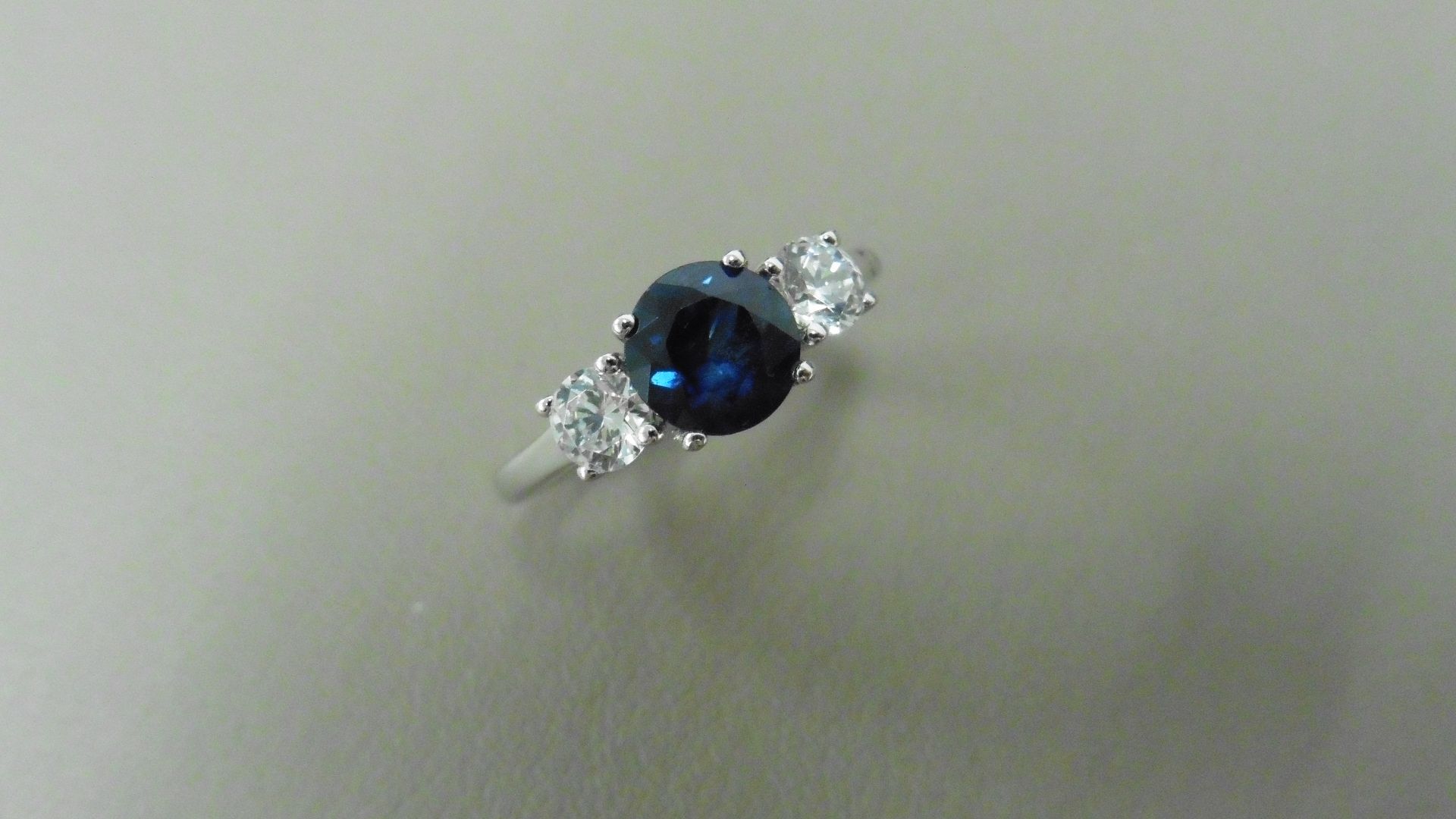 Platinum trilogy style ring. Round cut sapphire, 6mm in the centre (treated) 2 brilliant cut
