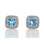 Blue topaz and diamond stud earrings. Cushion cut topaz surrounded by small brilliant cut