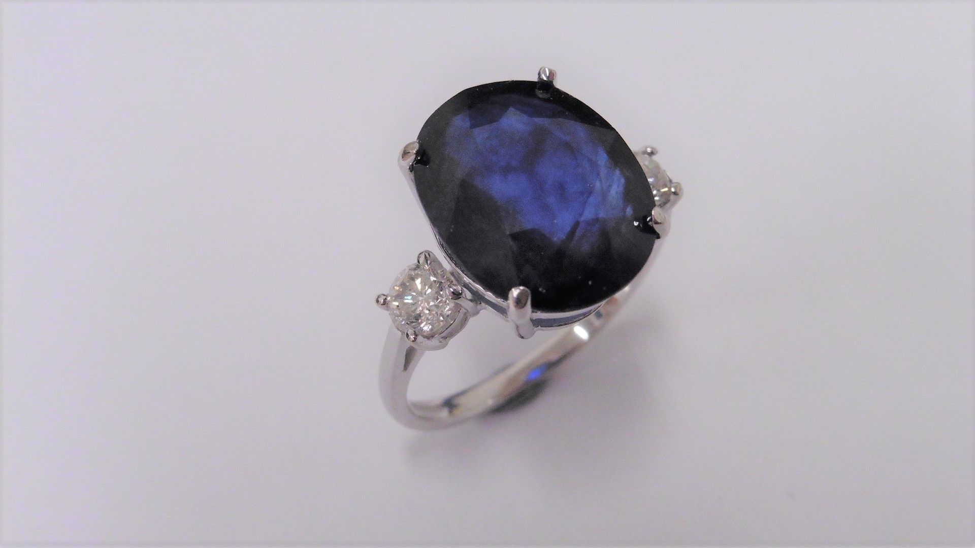 9ct sapphire and diamond trilogy ring set in platinum. Oval cut sapphire ( fracture filled ) with