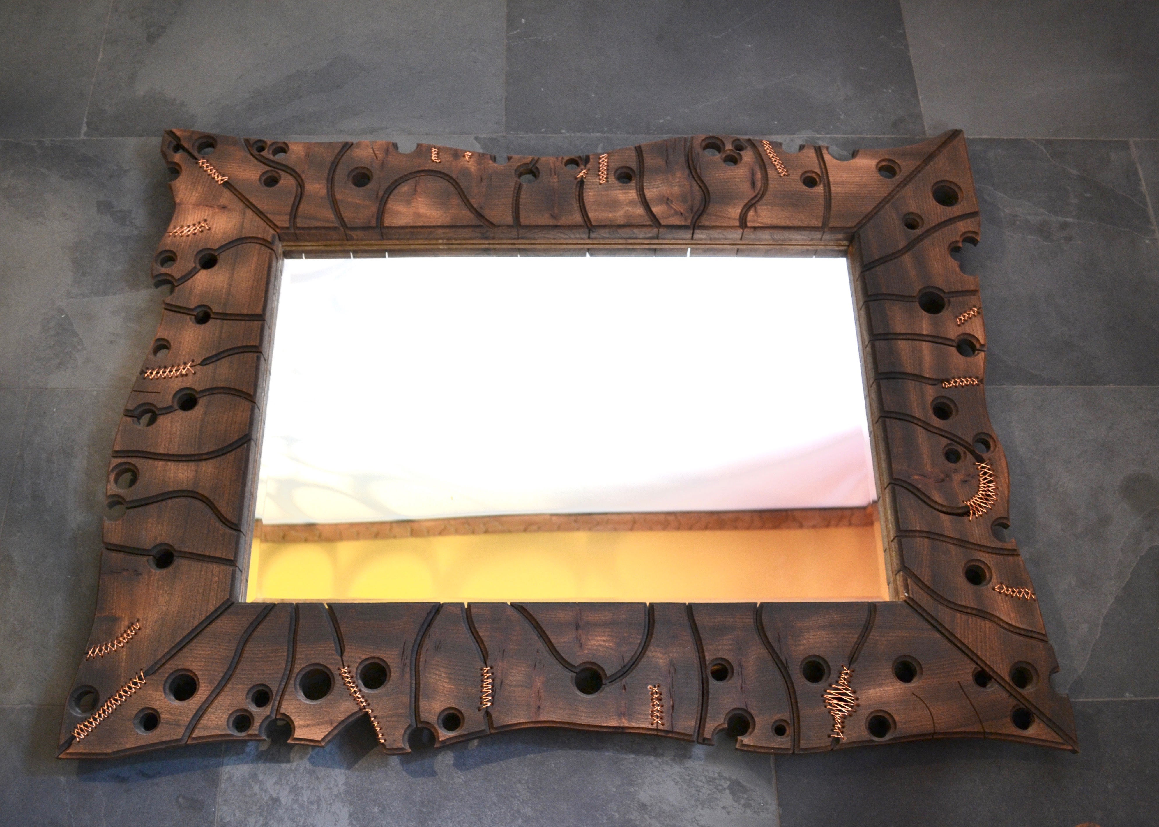 Malcom Lewis | This is an elm Swiss jigsaw mirror with copper stitching and measures 85cm x 110cm