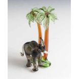 Glasfigur, Elefant unter zwei Palmen, Murano, Italien, farbig staffiert. H. ca. 14,5 cm, Br. ca. 9,5