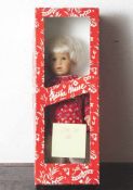 Käthe Kruse-Puppe, Mädchen mit kurzen blonden Haaren und braunen Augen, mit rot geblümtem Kleid