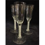 Three Georgian wine glasses with opaque twisted tape stems, two with damaged bases and one in good