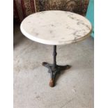 A cast iron tripod table with circular bevelled white marble top