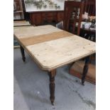 A pine kitchen table with central leaf extender.