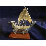 A small silver sailing ship on a stand
