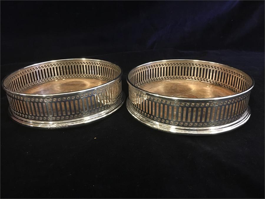 A pair of silver wine bottle coasters