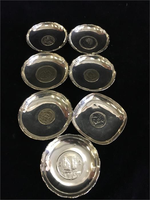 Seven silver dishes with central coin insets made in Hong Kong, total weight (394g)