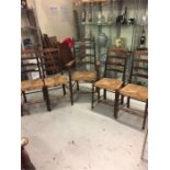 Four ladder backed rush seated chairs and one carver