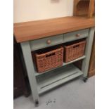 The Lambourn 2 Drawer French Grey Kitchen Trolley with beech top and wicker storage baskets and book