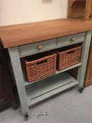 The Lambourn 2 Drawer French Grey Kitchen Trolley with beech top and wicker storage baskets and book