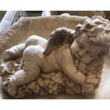 A garden stoneware cherub lying on a bed of grapes