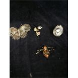 A white metal duck, white metal butterfly, amber ant brooch and a leaf brooch