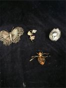 A white metal duck, white metal butterfly, amber ant brooch and a leaf brooch