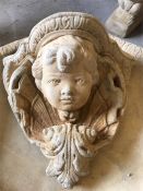 A stoneware garden wall mounted cherub's face planter