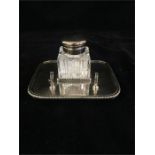 A silver plated and glass inkwell on stand with pen rest.