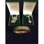 Two boxed silver chains, one with a heart locket and a silver bangle