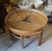 A Mid Century circular glass topped coffee table with three side tables under.