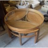 A Mid Century circular glass topped coffee table with three side tables under.