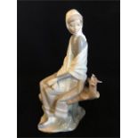 A Lladro figure of a lady in a shawl with a bird.