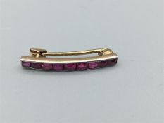 9 stone ruby, square cut, in 22mm long gold bar.