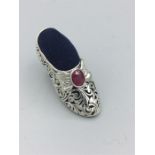 A silver pin cushion in the form of Victorian shoe inset with a ruby buckle