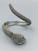 An Unusual silver and marcasite snake bangle incorporating a watch with ruby eyes
