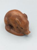 A Carved wooden netsuke in the horm of a pig signed to the base