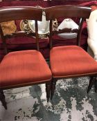 A pair of mahogany chairs with orange seat pads