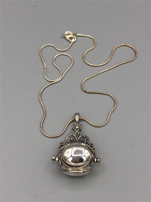 A silver revolving locket on a silver chain