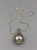 A silver revolving locket on a silver chain