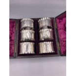 A boxed set of six silver napkin rings