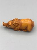 A wooden Netsuke in the form of a pig, signed on the undeside