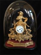 A Camerer & Kuss gilt clock under a glass dome.