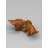 A wooden Japanese Netsuke in the form of a fish signed to the base