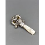 A silver babies rattle with mother of pearl handle