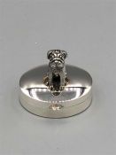 A silver pill box with bear to the lid