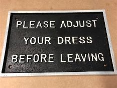 A cast iron 'Please adjust your Dress' sign