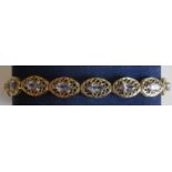 A tanzanite and yellow gold line bracelet. The sixteen Marquise-set tanzanite stones assessed pale