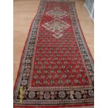 A Persian hand-knotted Hamadan scarlet-ground wool runner with multicoloured floral and foliate