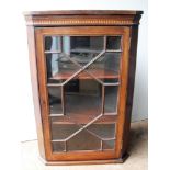 A 19th century mahogany hanging corner unit with crossbanding to frieze, astragal door and shelved
