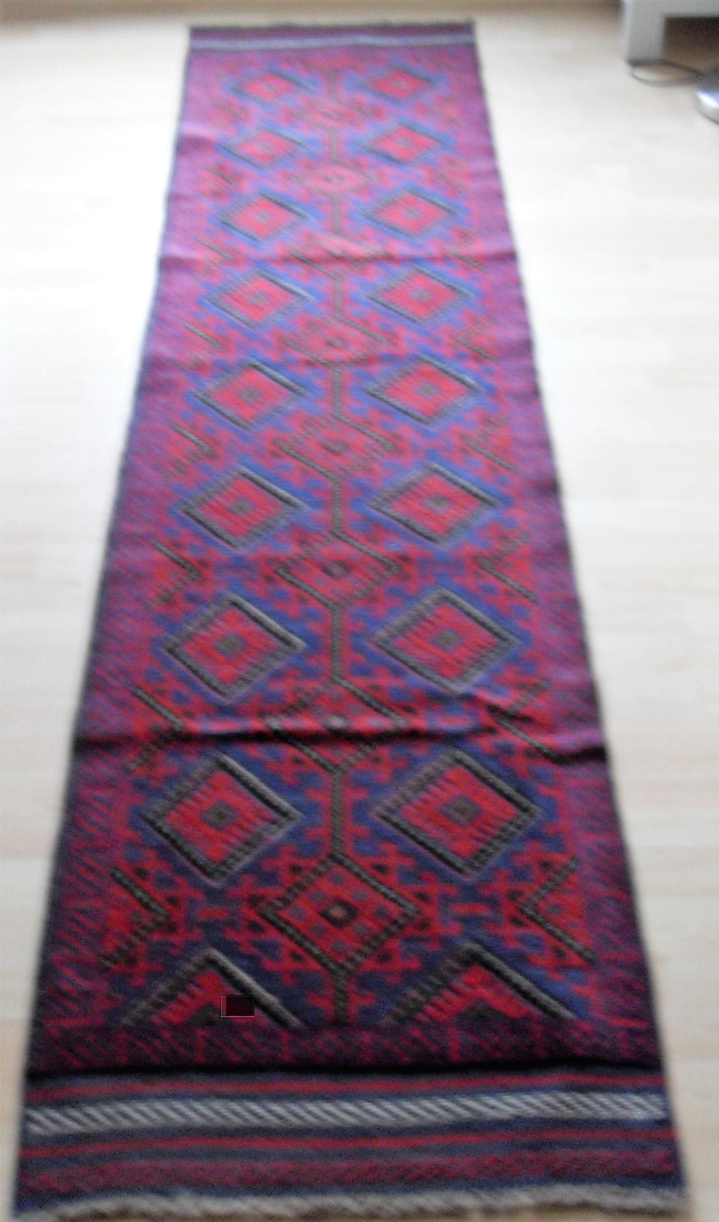 An Afghan hand-knotted Meshwani blue-ground wool runner with multi-coloured lozenge designs,