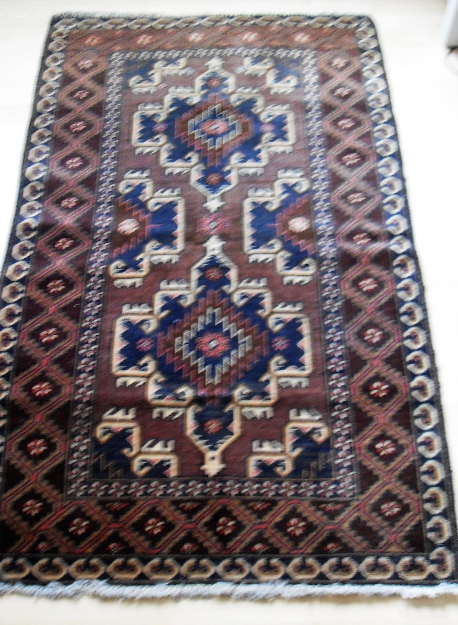 An Afghan hand-knotted maroon-ground Herathi Balochi wool rug with isometric designs, double