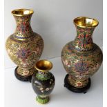 A small cloisonne vase with elaborate decoration and a pair of taller vases with flared rims on