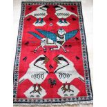 A hand-knotted scarlet-ground tribal pictorial rug with single border and short fringe, 85 x 134